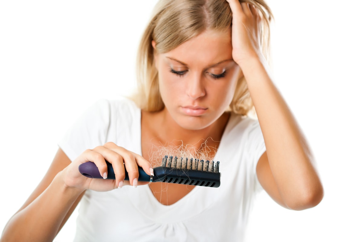 Frau hält Bürste mit Haarbüschel